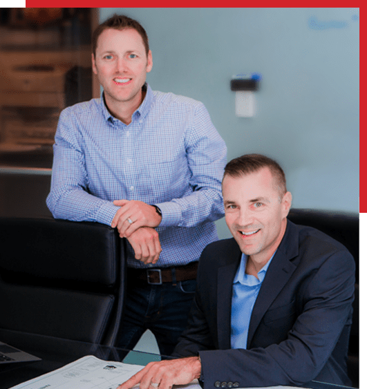 Two men smiling in front of a desk.