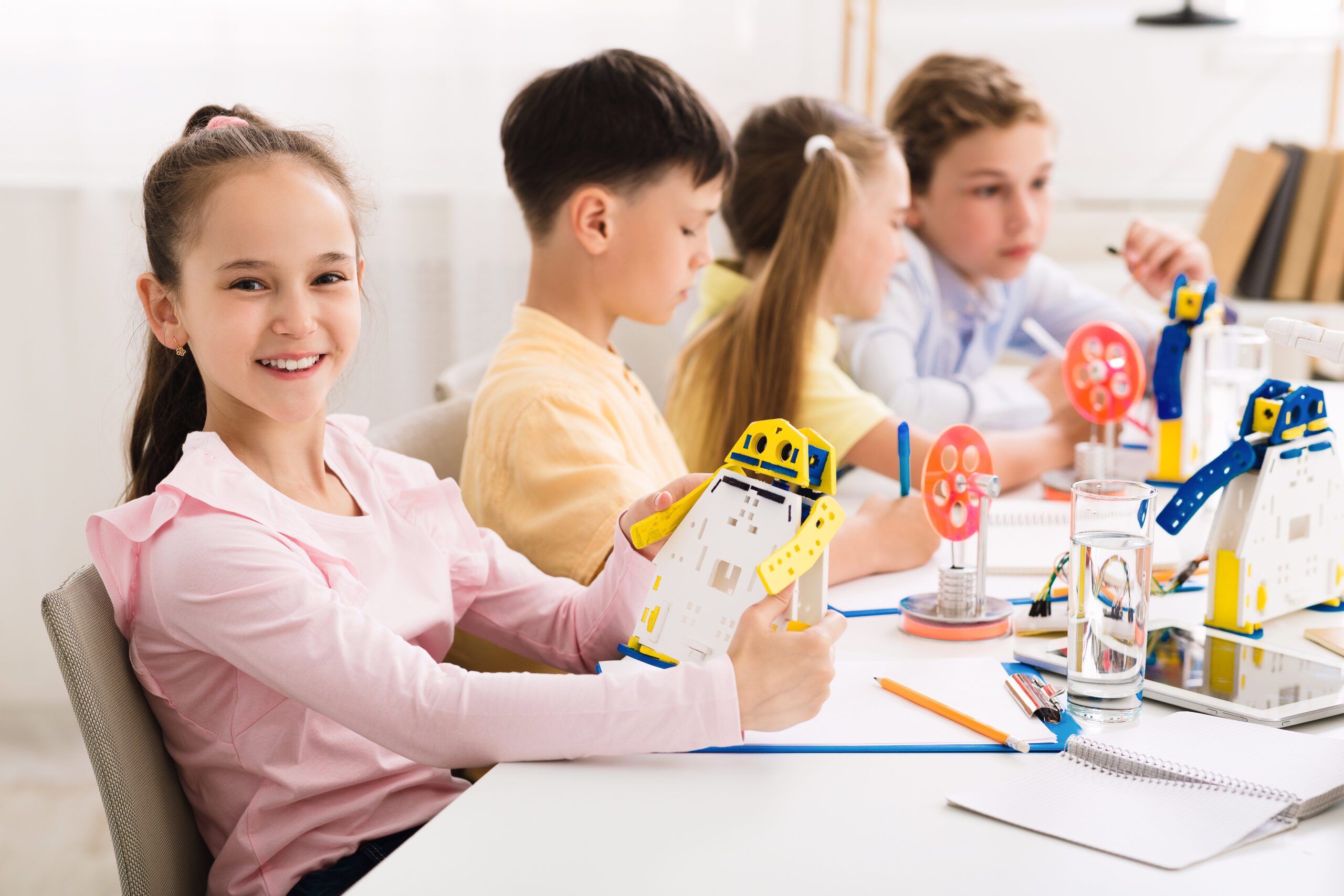 A group of children are sitting at a table making toys.