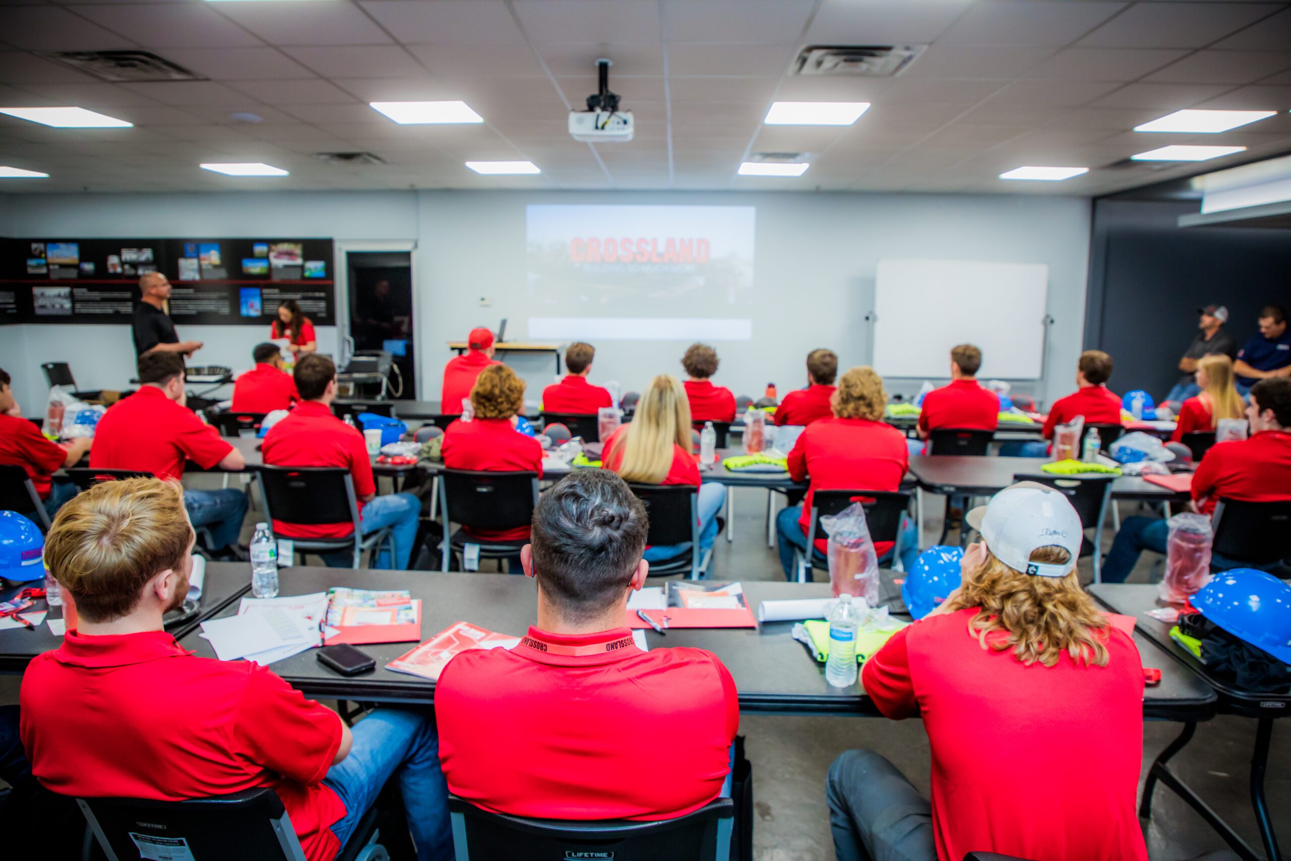 A group of people in red shirts in a classroom.