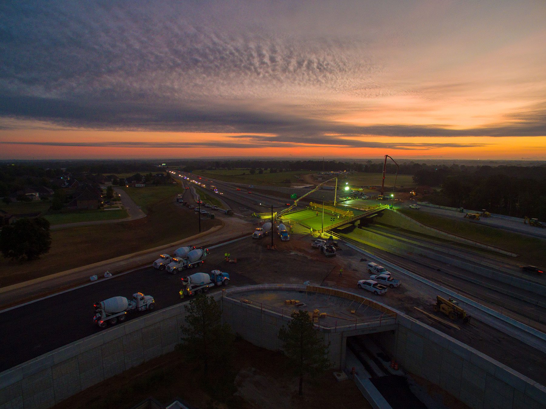 Bird's eye view of concrete trucks pouring concrete on a job site at night.