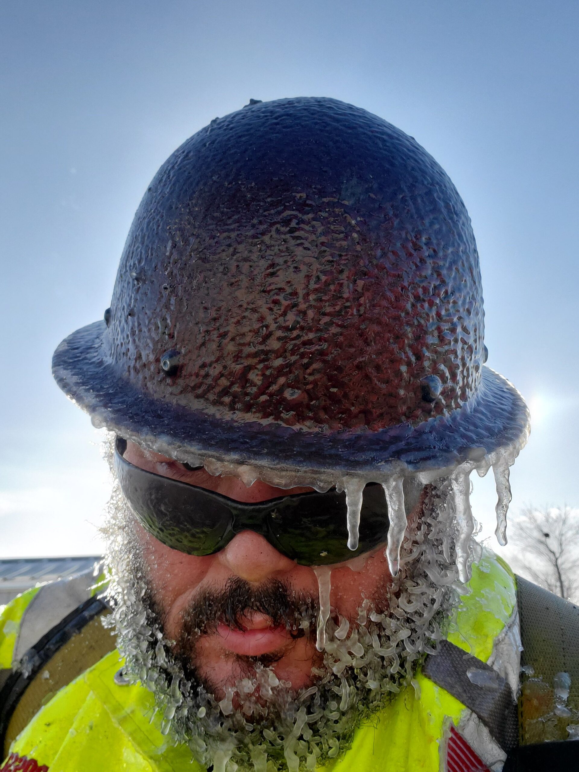 A construction working wearing a hat covered in ice.