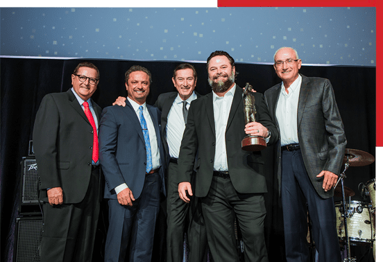 A group of men posing for a picture with an award.