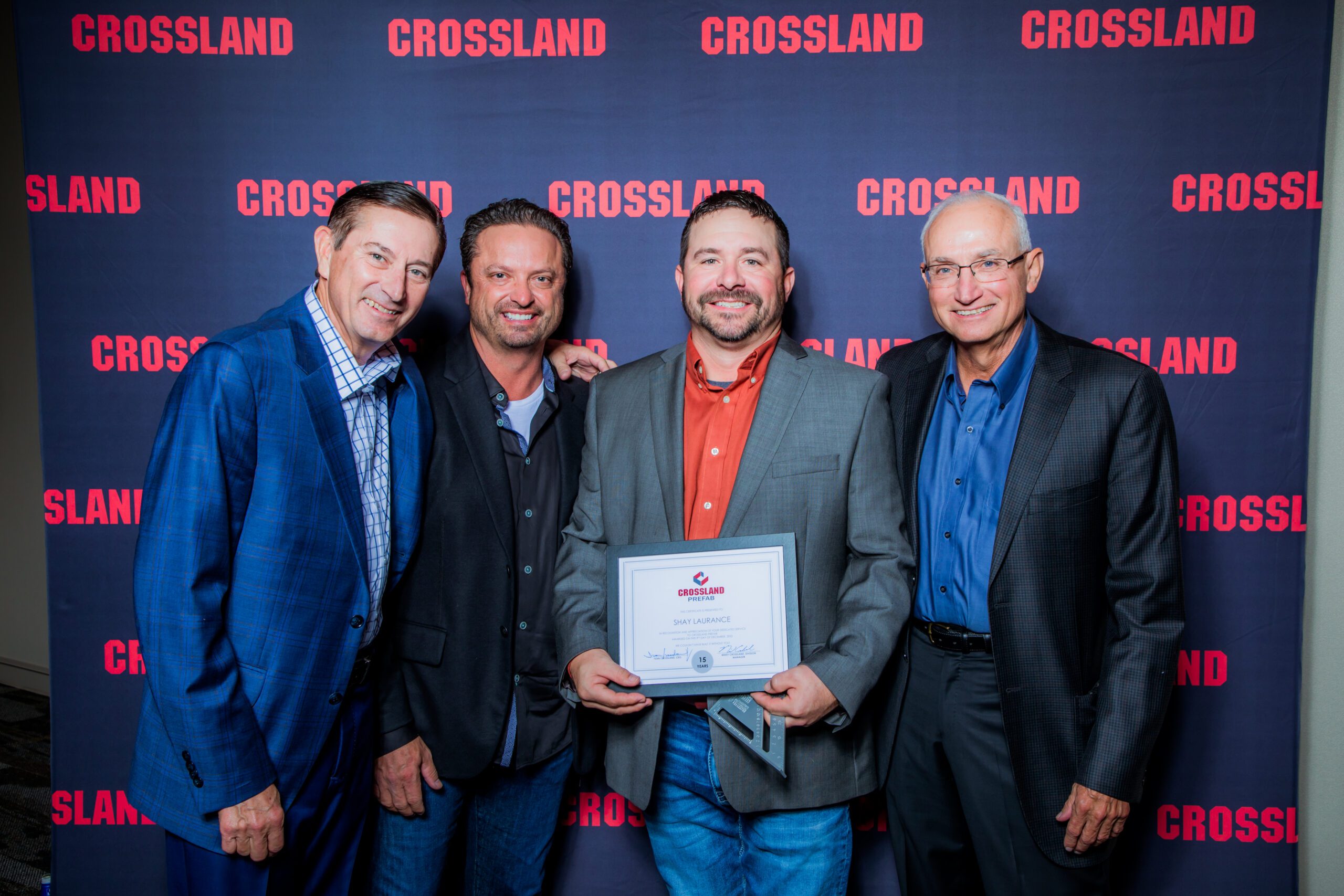 A group of men posing for a picture in front of a Crossland banner.