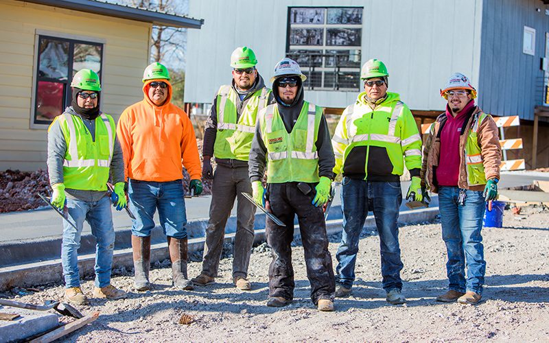 A group of construction workers standing in front of a house.