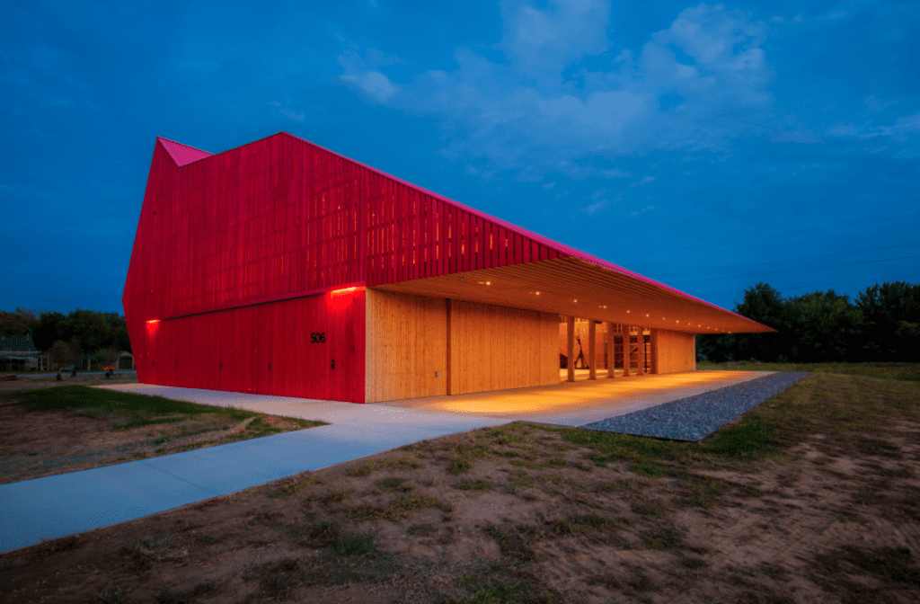 A red building in the middle of a field at night.