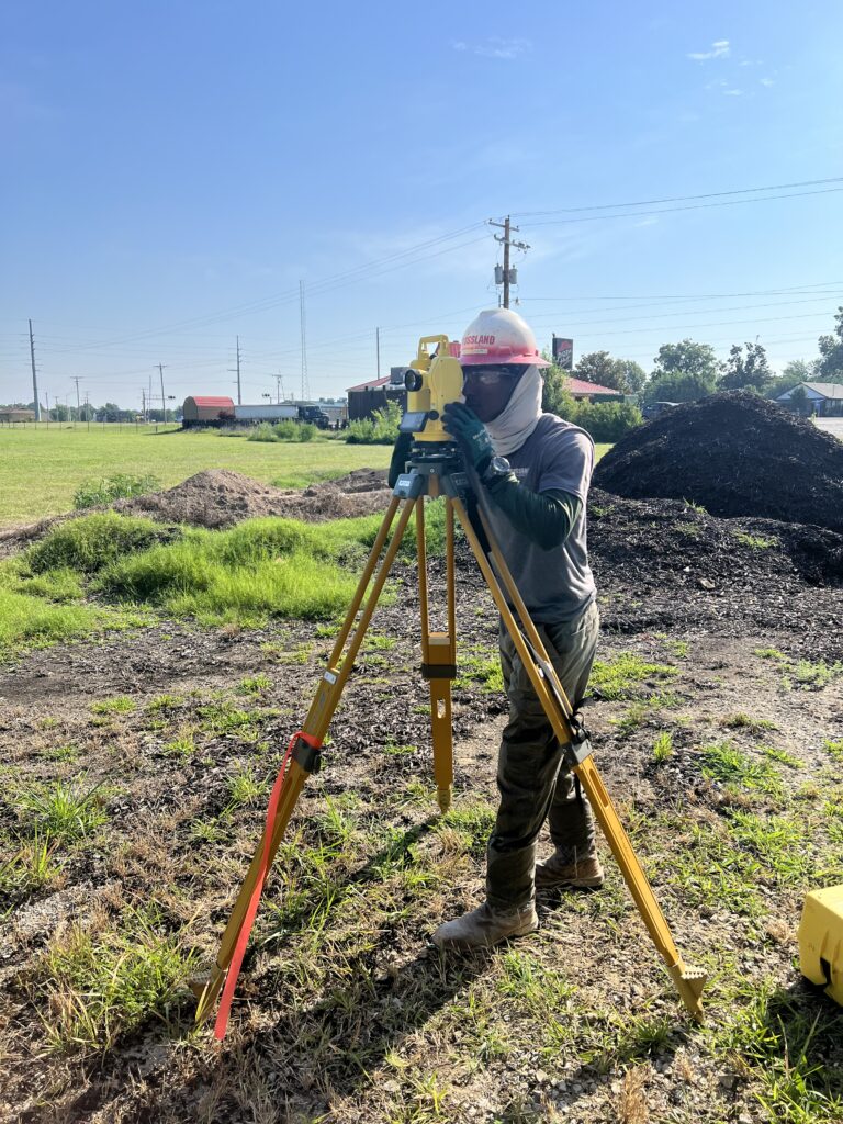 A man with a surveyor's equipment in a field.