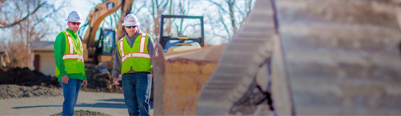 Two construction workers wearing PPE on a job site.