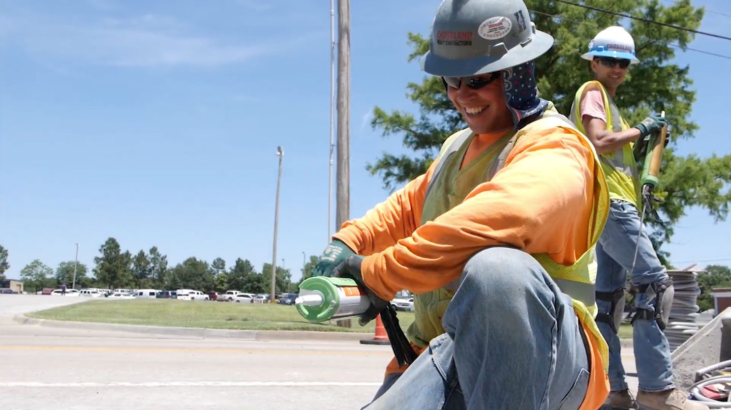 Construction workers wearing PPE and smiling as they work.