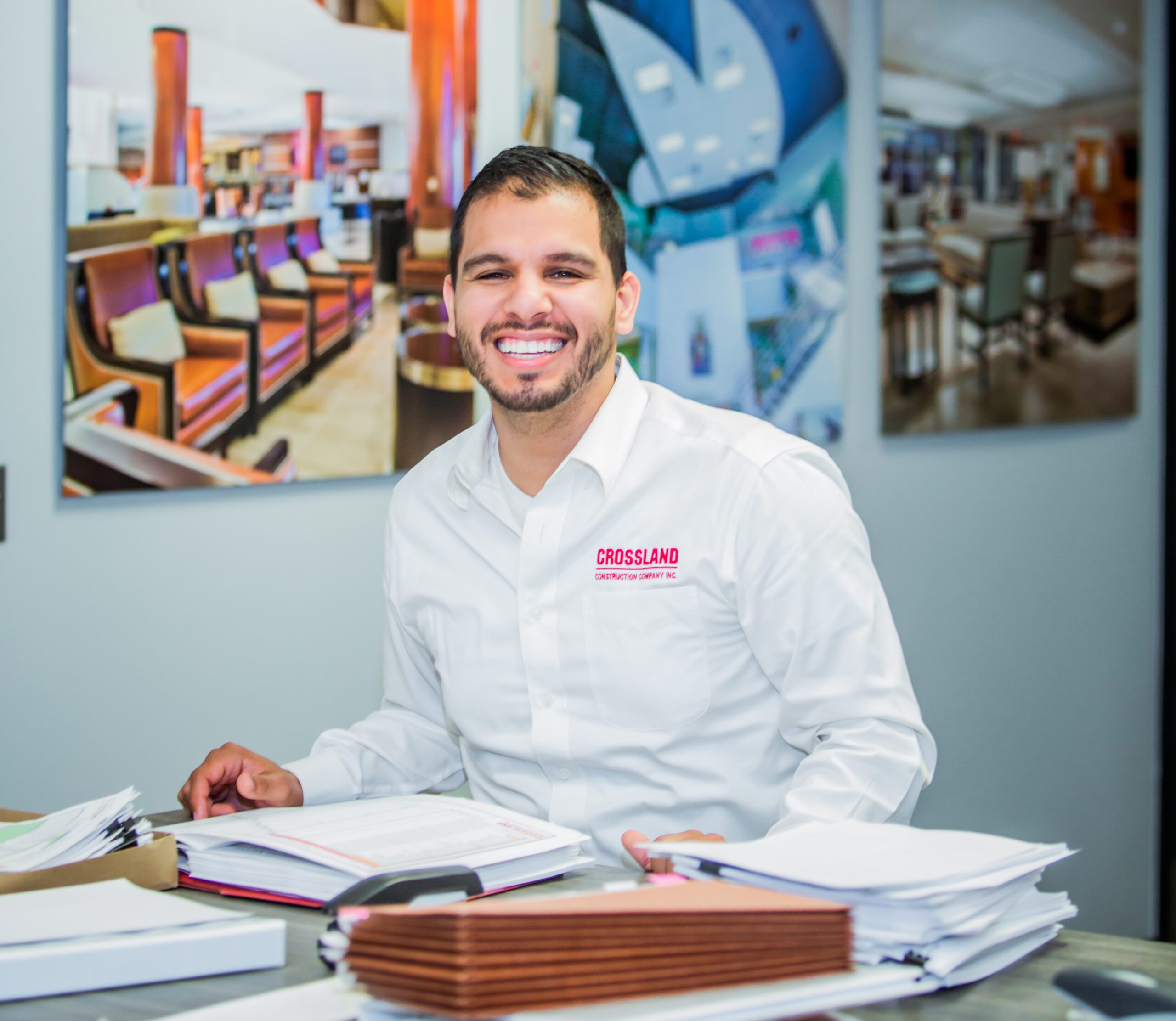 ݮConstruction employee smiling as he works at desk.