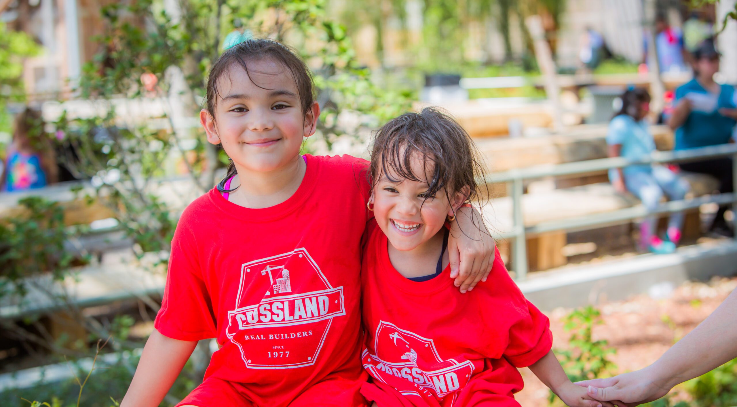 Two young girls in red shirts are posing for a picture.