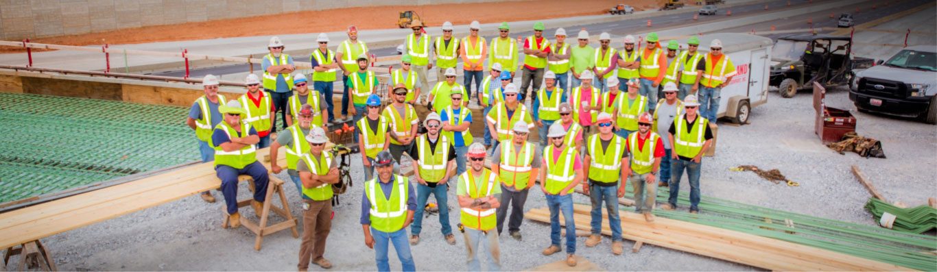 Group of ݮconstruction workers wearing PPE posing on a job site.