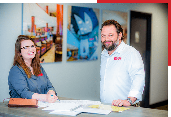 A man and woman standing in front of a desk.