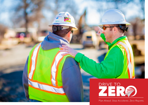 Two construction workers wearing PPE outside.