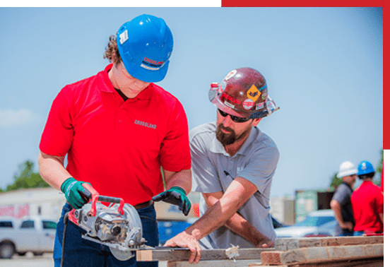 Two men working on a piece of wood.