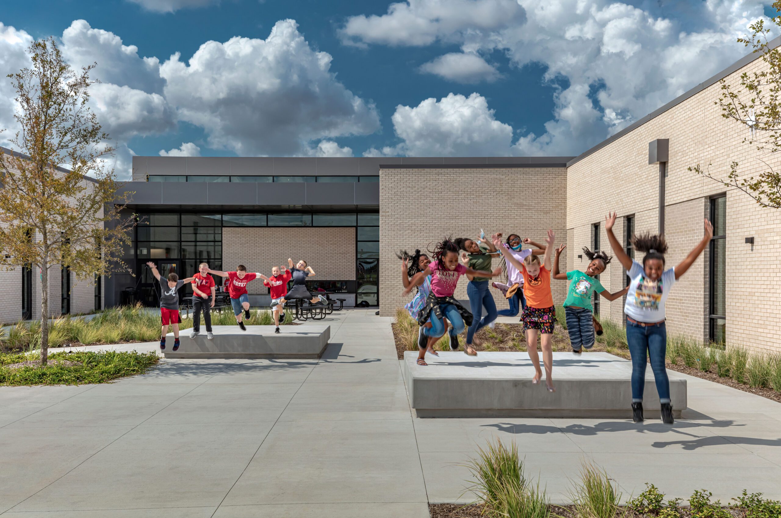 A group of children are jumping in front of a building.